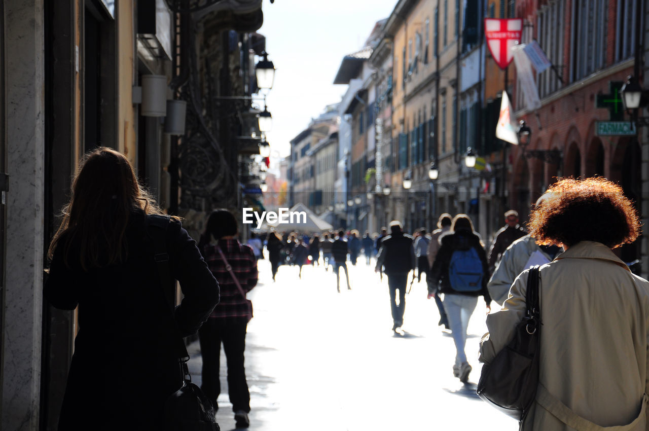 Pedestrians walking on city street amidst buildings in italy.