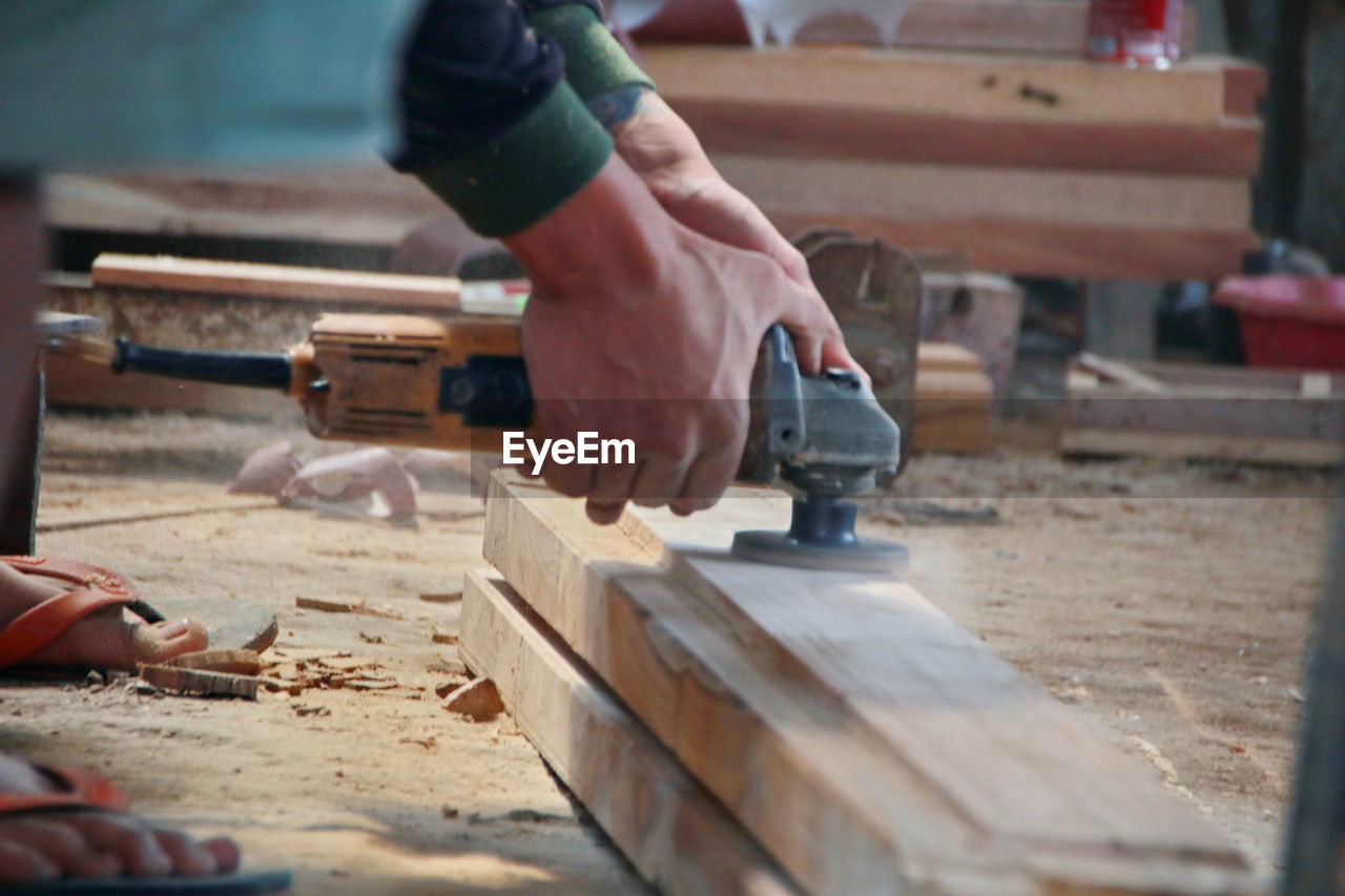 Low section of man working on wood in workshop