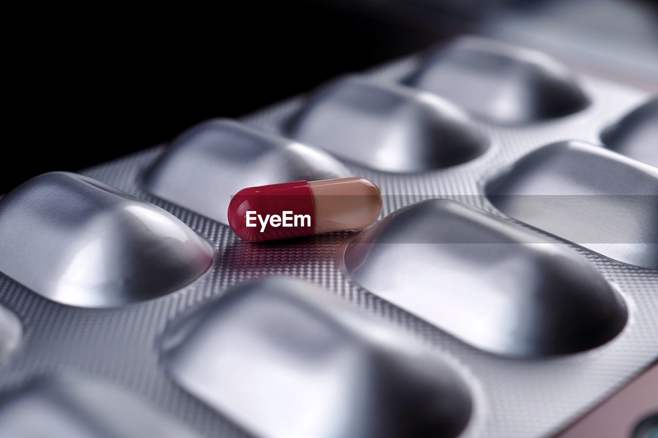 Medicine panel pill treatment of pink capsule on black background.