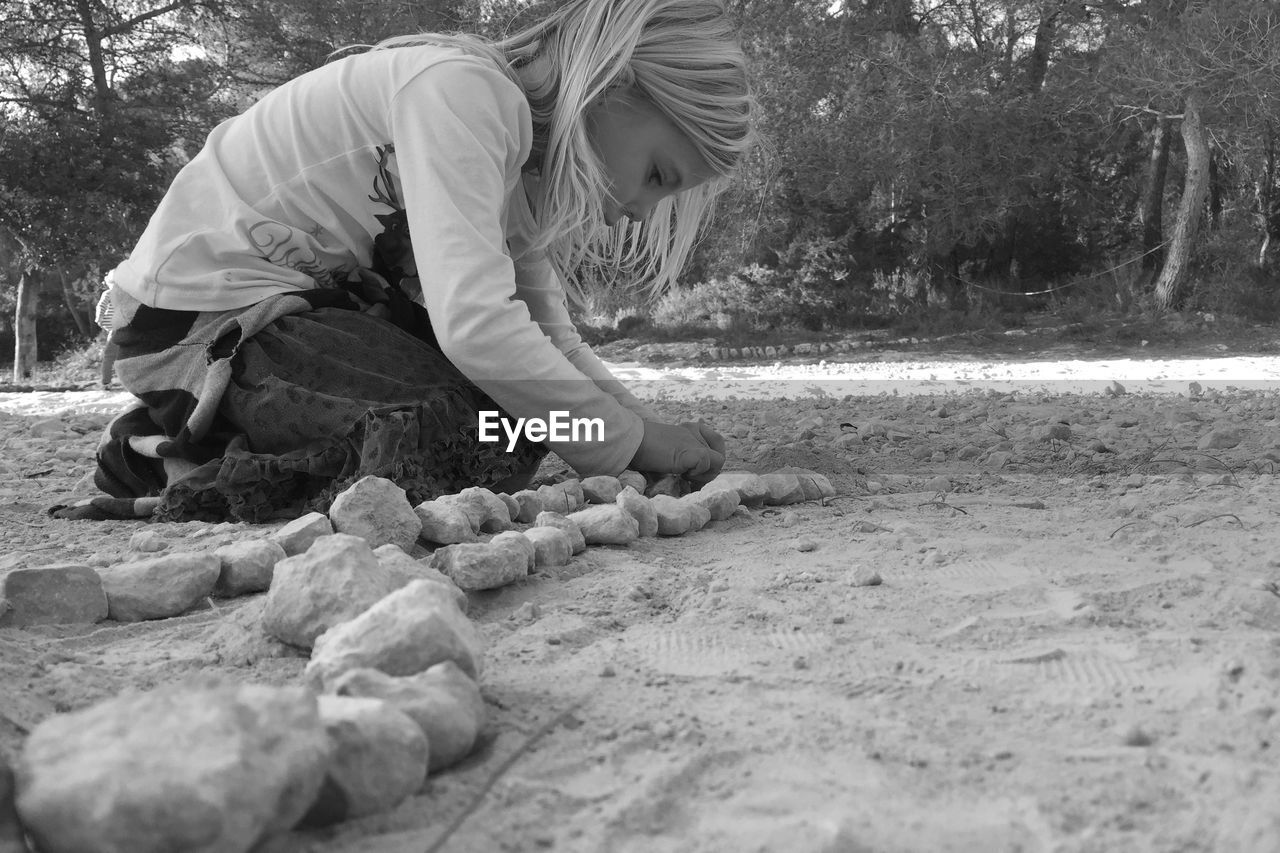 Side view of girls arranging rocks on field