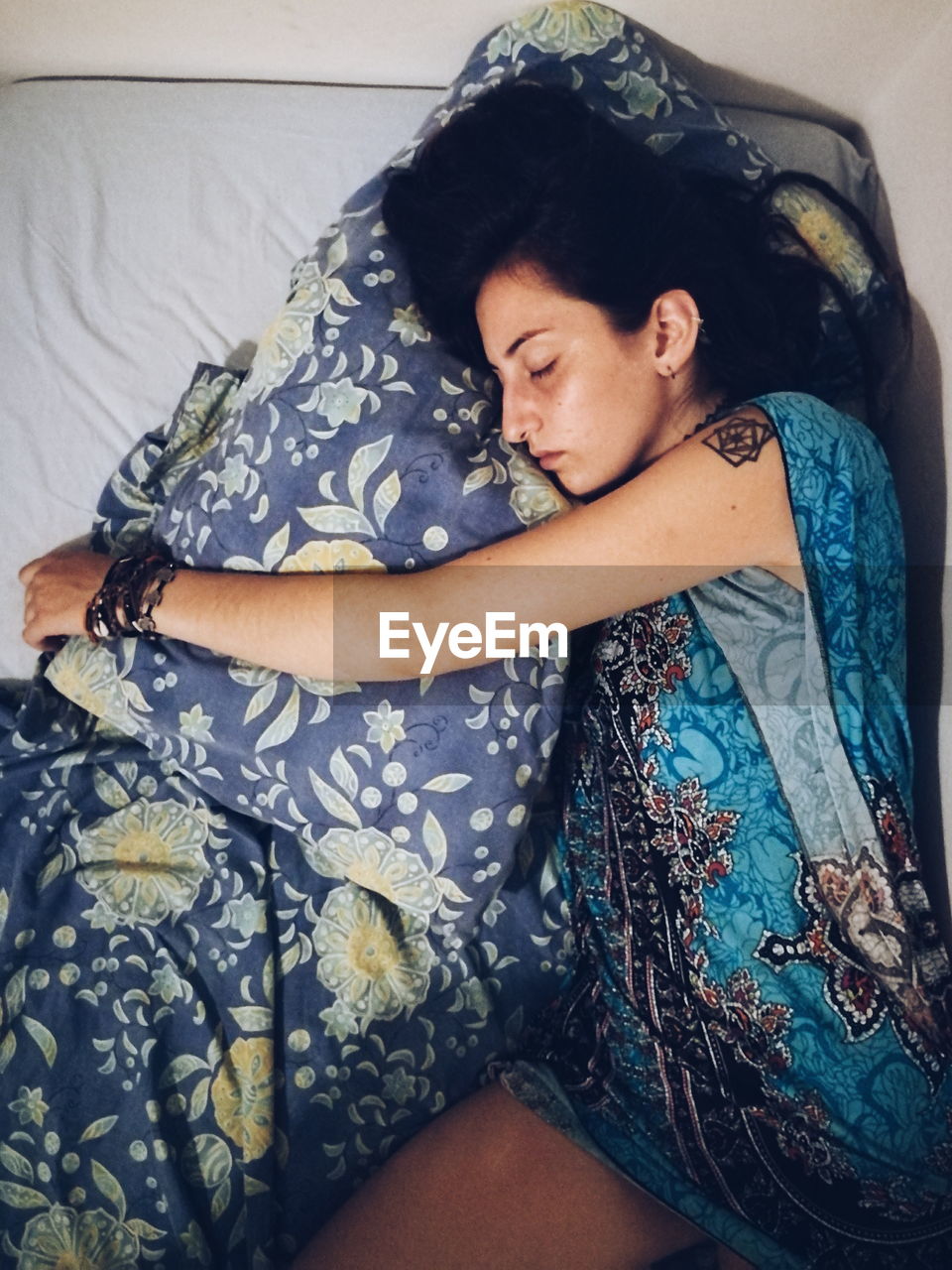 High angle view of young woman sleeping on bed