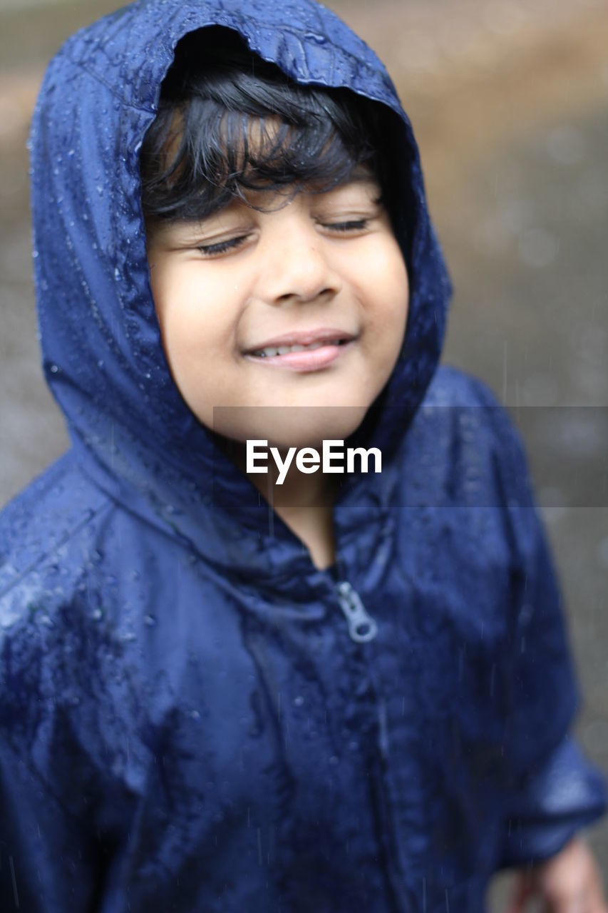 High angle view of boy wearing raincoat enjoying rain