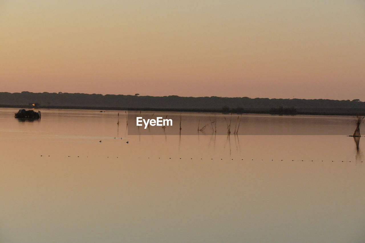 SCENIC VIEW OF LAKE AGAINST SKY AT SUNSET