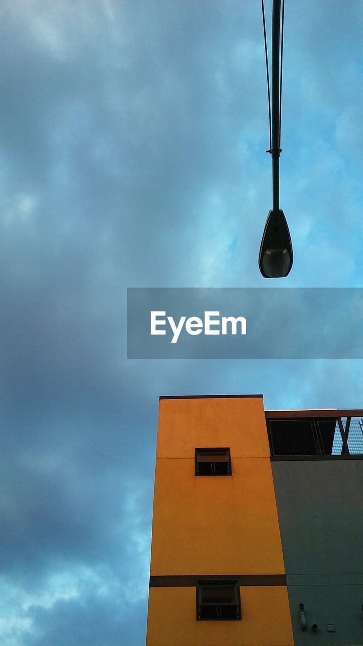 LOW ANGLE VIEW OF STREET LIGHT AND BUILDING AGAINST CLOUDY SKY