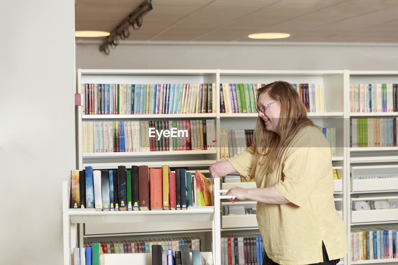 Librarian pushing book trolley forward