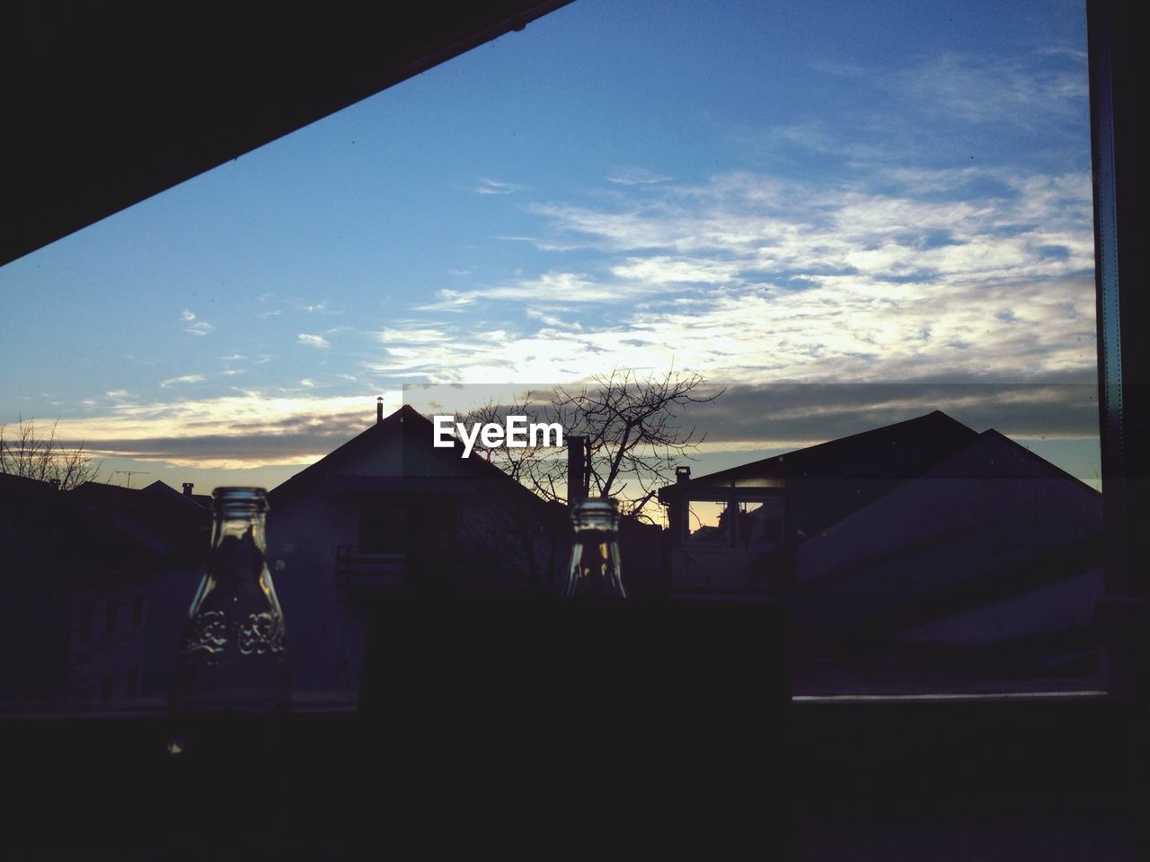 Houses against cloudy sky seen through window