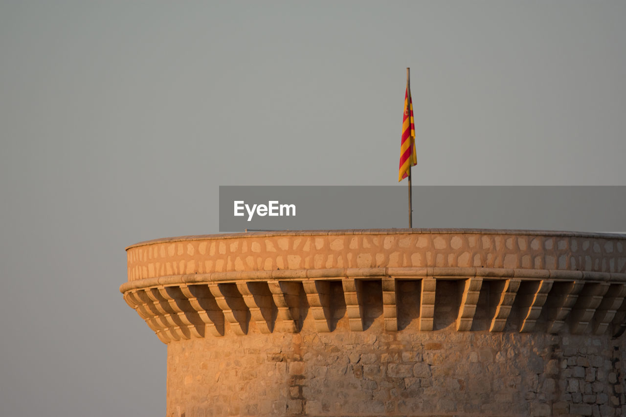 Flag on top of tower against clear sky