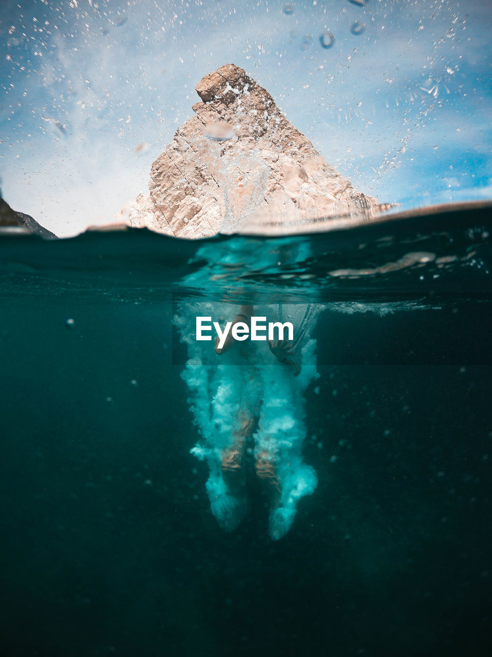 Person swimming in sea against mountain