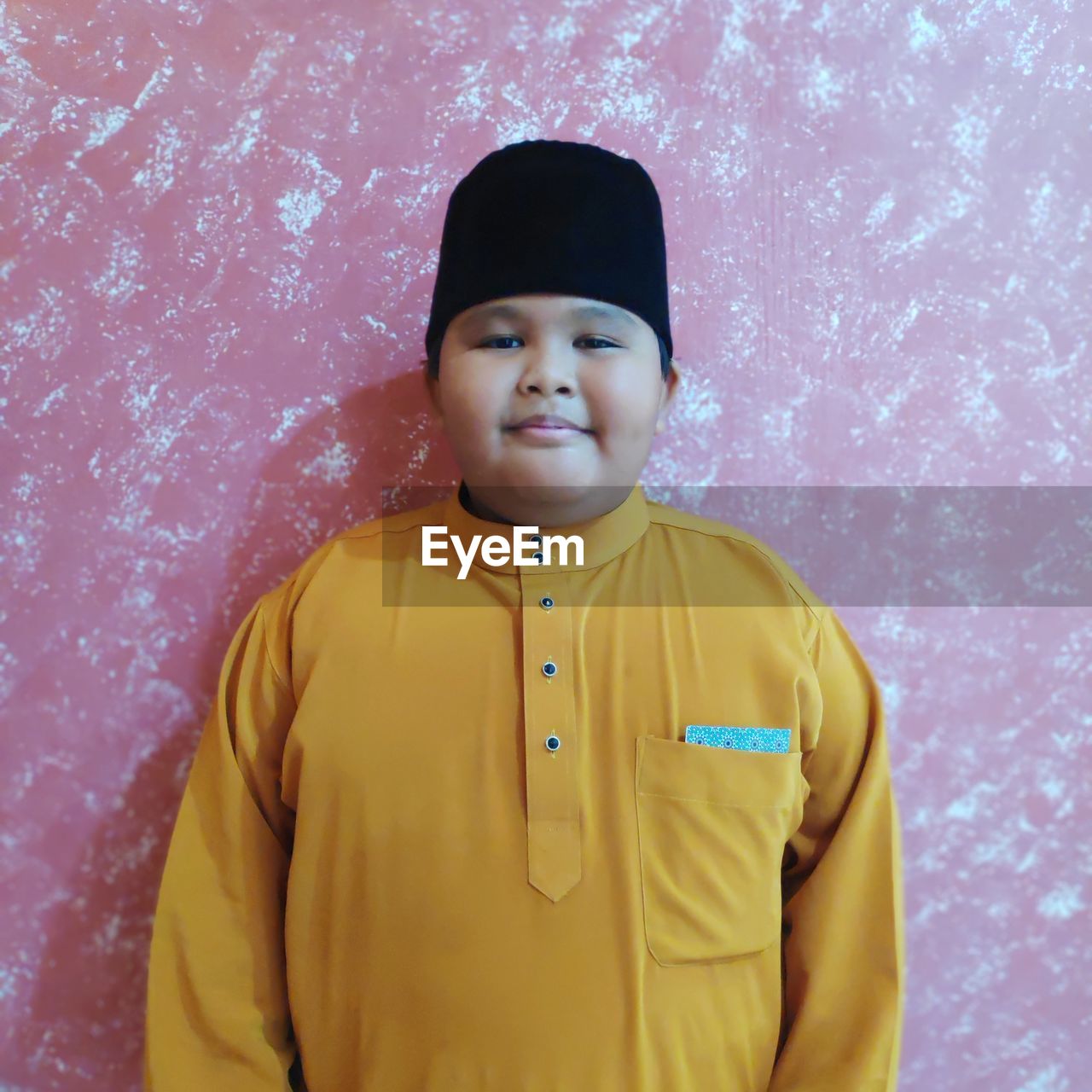 PORTRAIT OF SMILING GIRL STANDING AGAINST YELLOW WALL