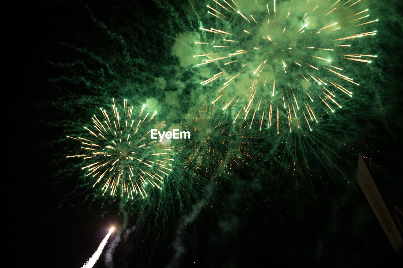 LOW ANGLE VIEW OF FIREWORK DISPLAY OVER WATER