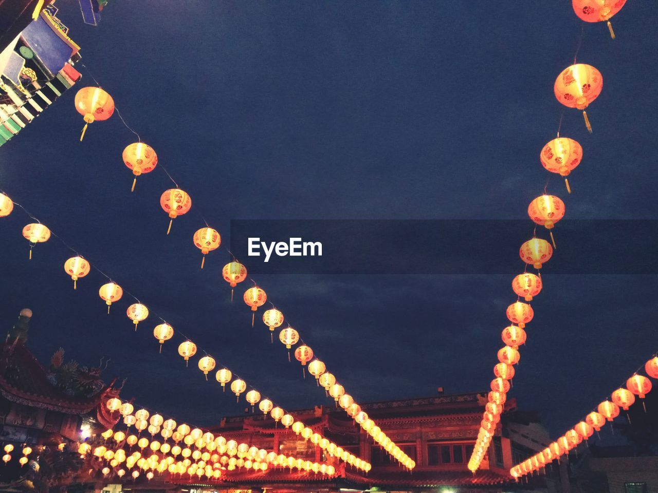 LOW ANGLE VIEW OF ILLUMINATED LANTERN HANGING AGAINST SKY