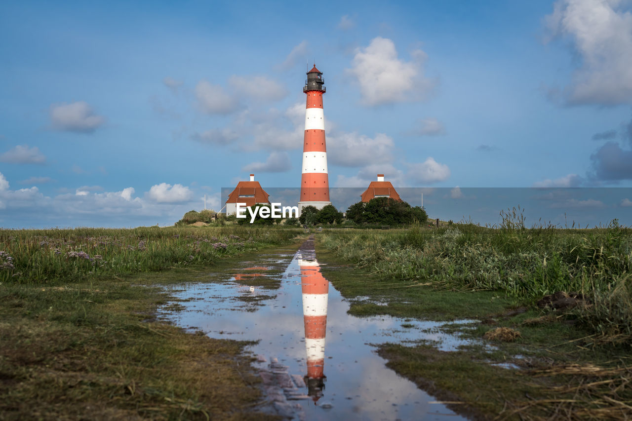 Lighthouse by sea against sky