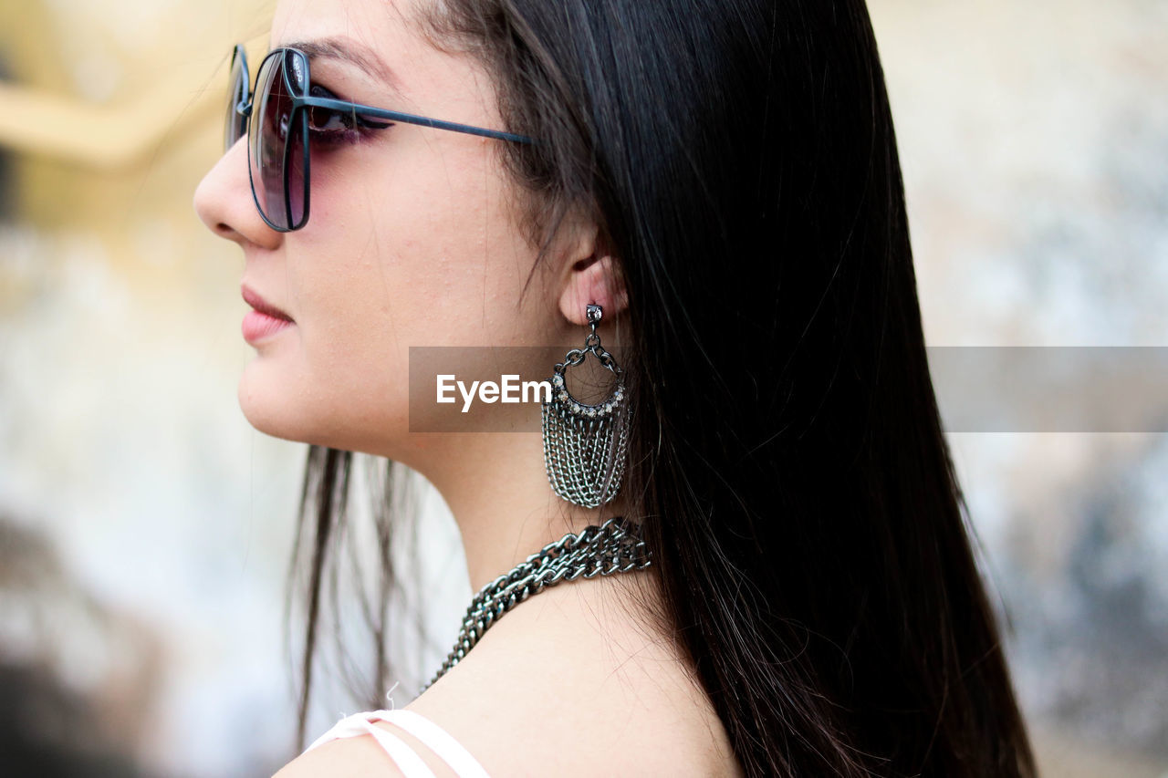 Close-up of beautiful young woman wearing sunglasses while standing outdoors
