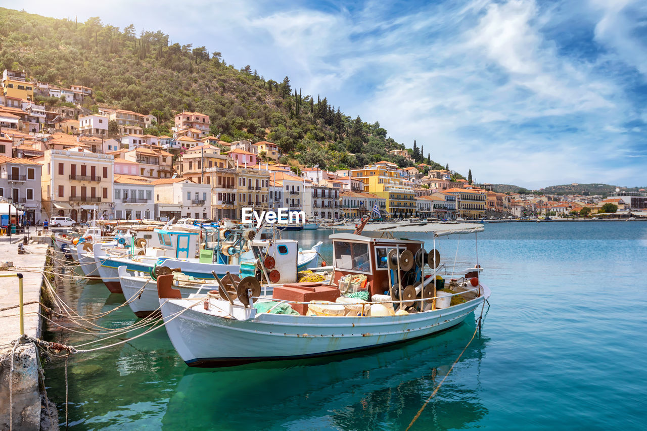 BOATS MOORED IN SEA AGAINST SKY IN CITY