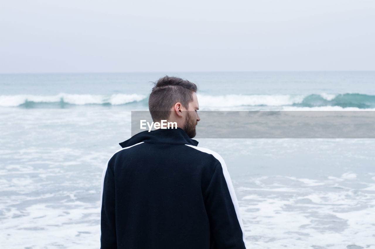 Rear view of man at beach against sky