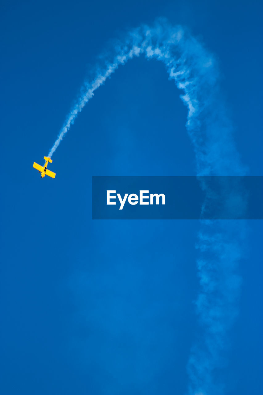 Low angle view of airplane flying against clear blue sky