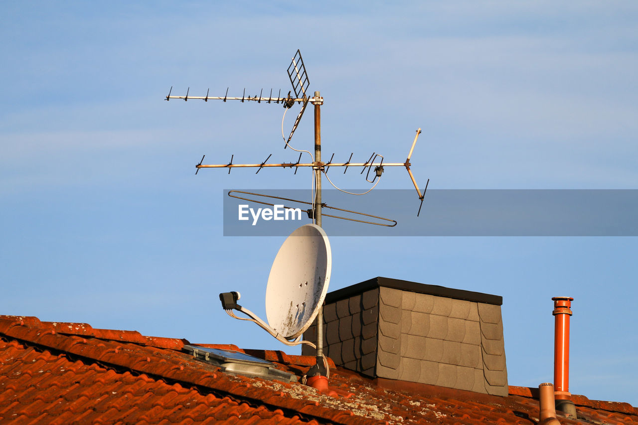 Tv antenna and satellite dish on an old house roof
