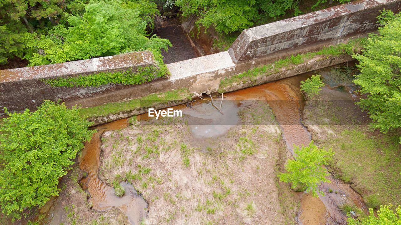 HIGH ANGLE VIEW OF BRIDGE OVER LAKE AGAINST TREES