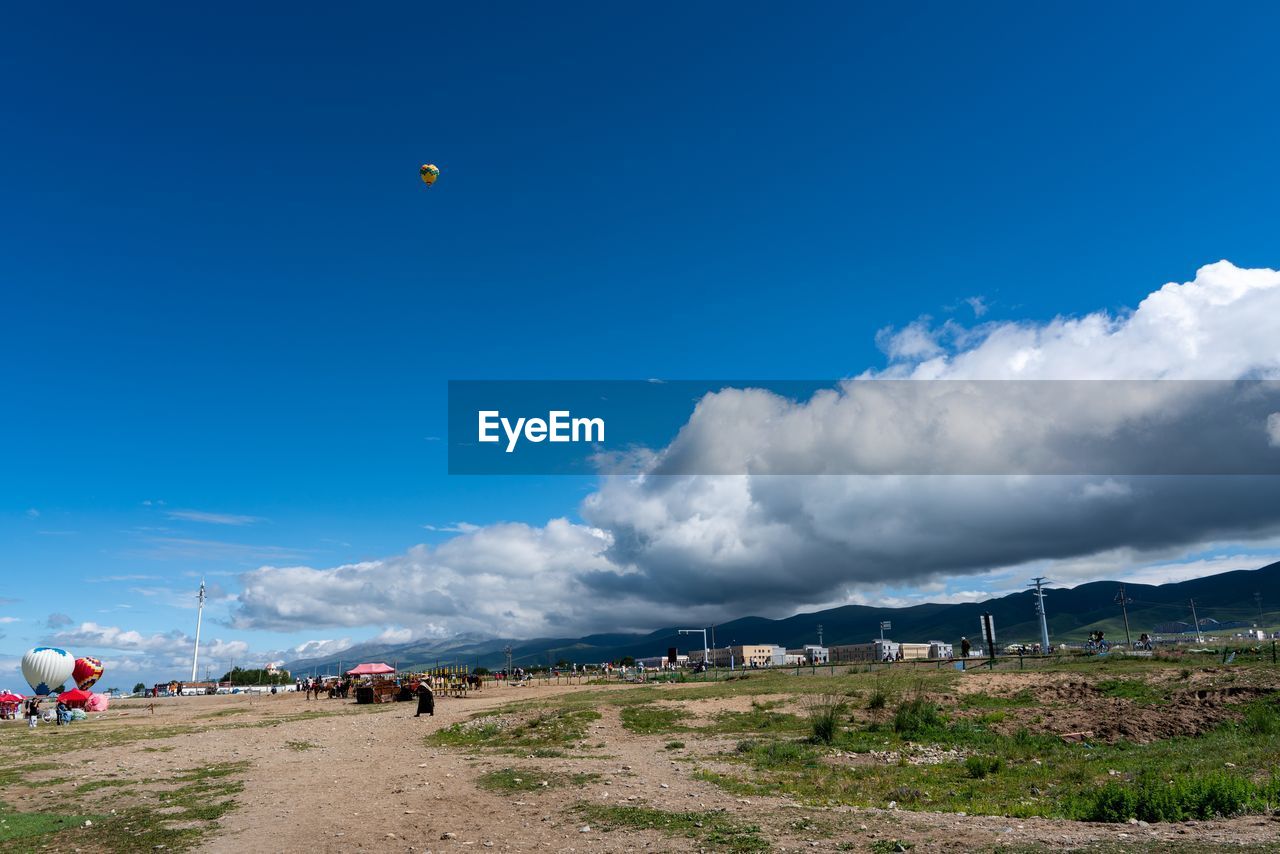 PEOPLE ON LAND AGAINST BLUE SKY