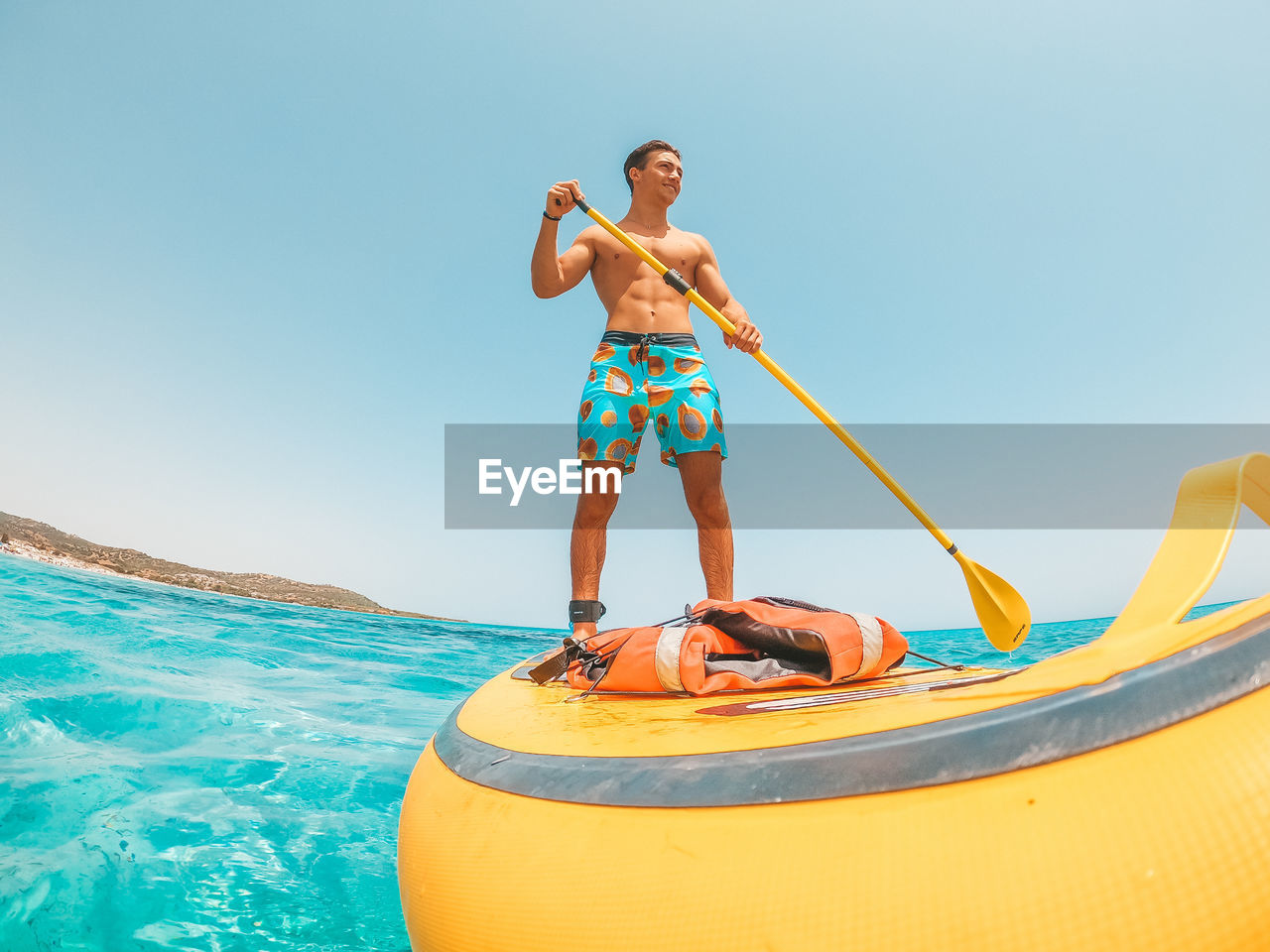 MAN STANDING BY SEA AGAINST CLEAR SKY