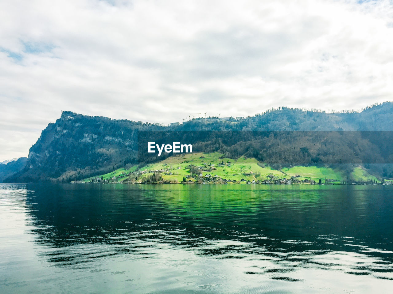 Scenic view of lake and mountains against cloudy sky