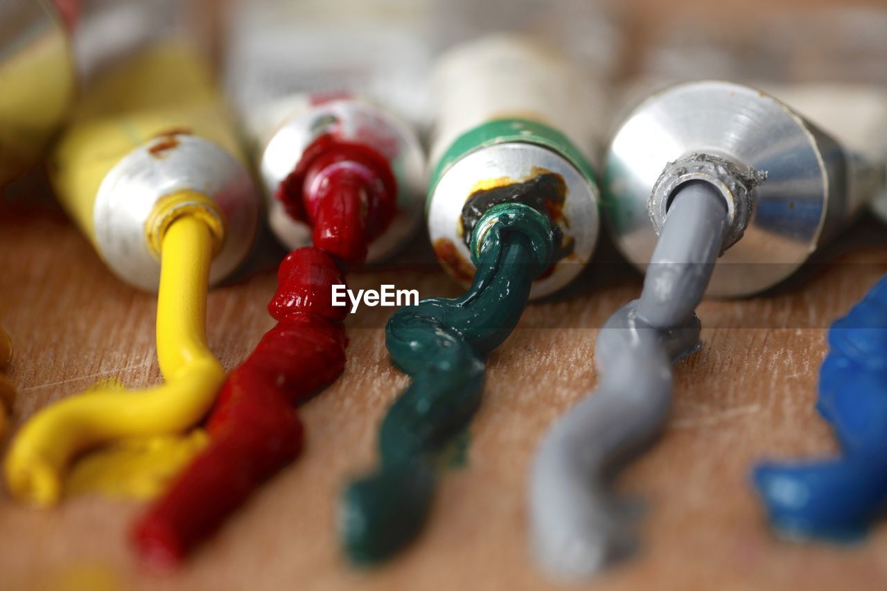 Close-up of colorful paints spilled from tubes on wooden table