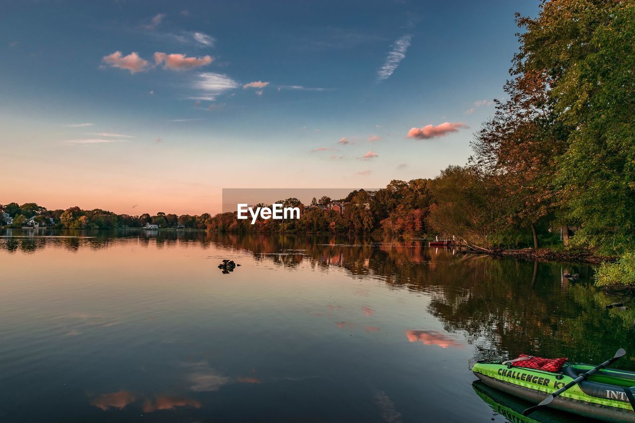 BOATS MOORED ON LAKE BY TREES AGAINST SKY