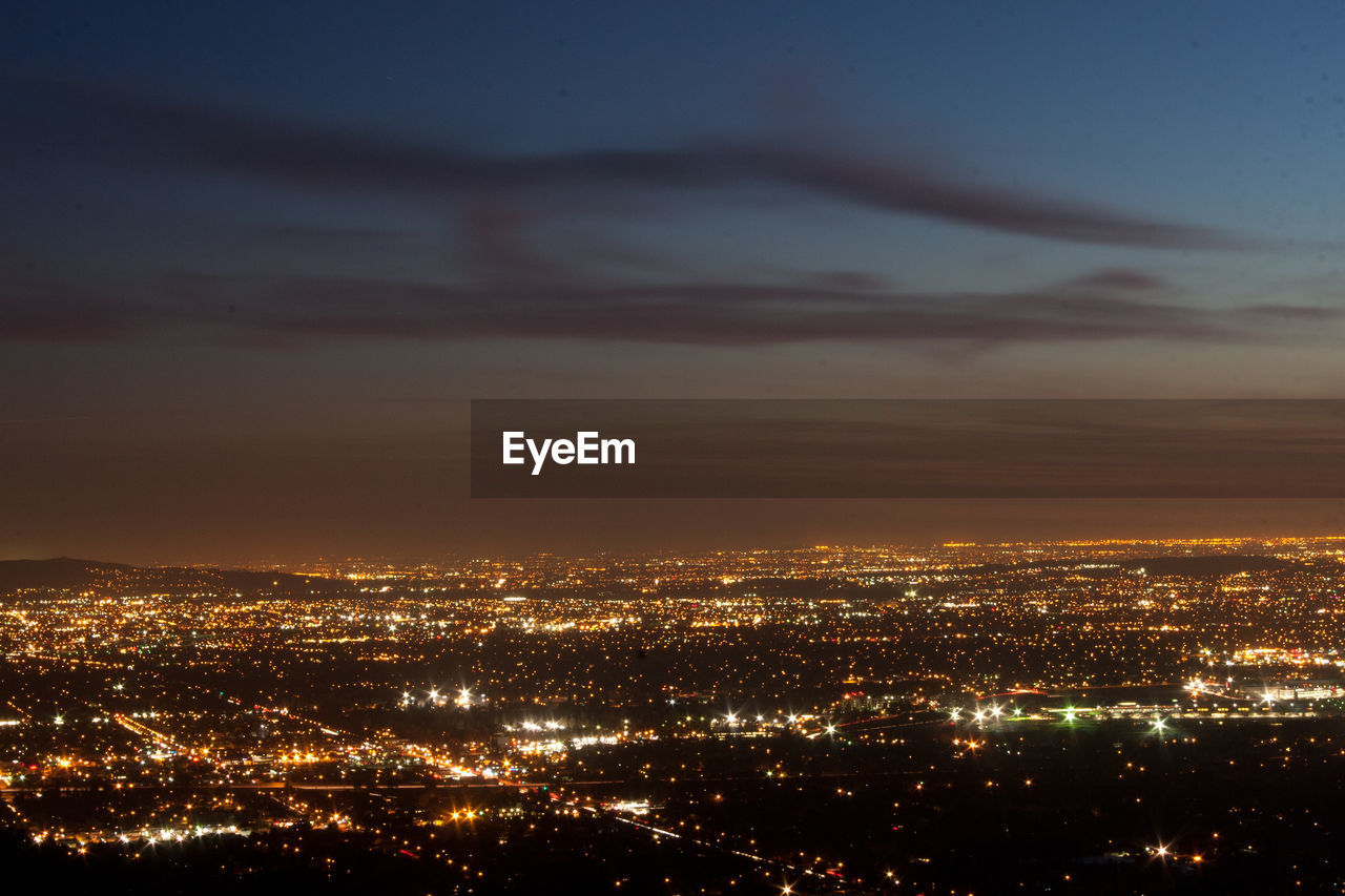 HIGH ANGLE VIEW OF ILLUMINATED CITY BUILDINGS AT NIGHT