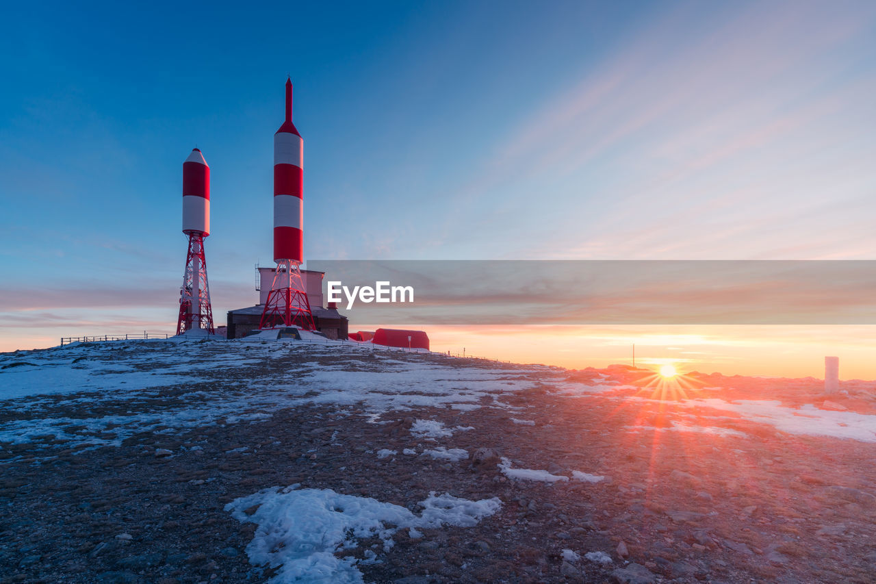 Station with radio and television signal repeater antennas with curious rocket shape located on snowy mountain on winter day in spain