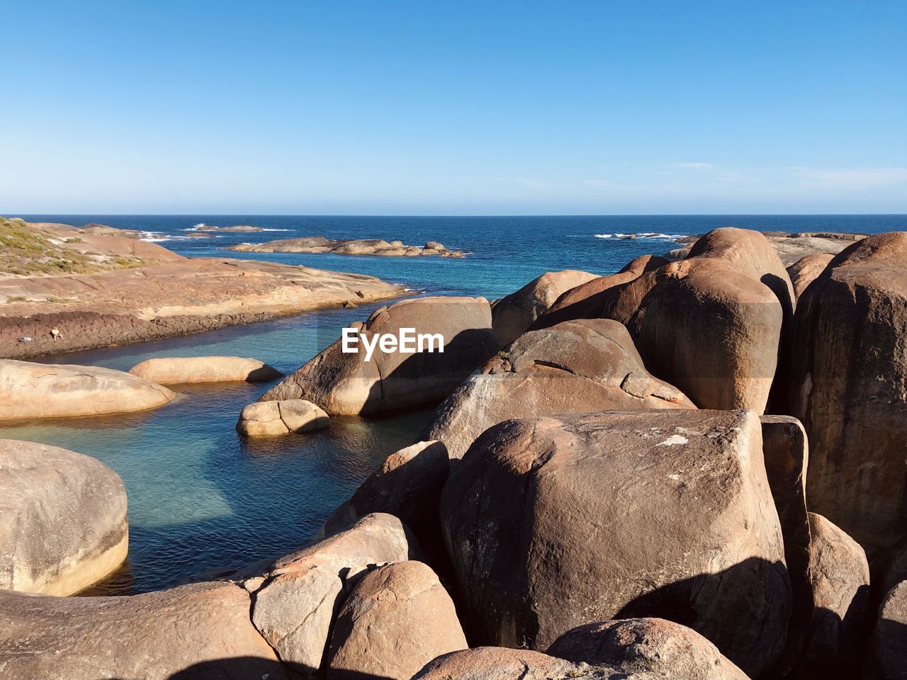 ROCKS BY SEA AGAINST SKY