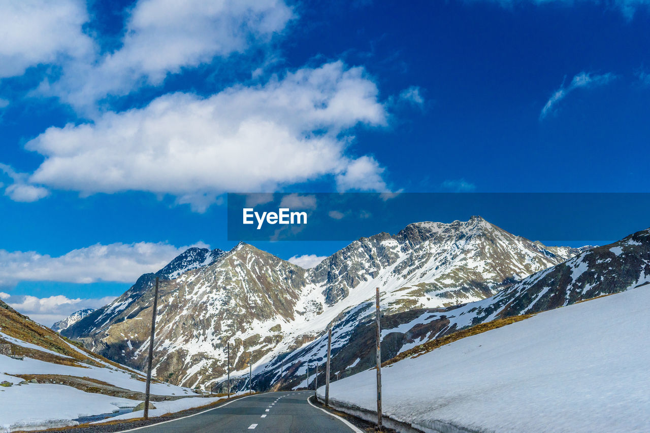 ROAD BY SNOWCAPPED MOUNTAIN AGAINST SKY