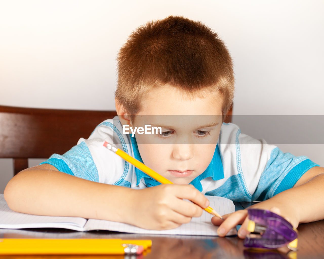 Boy writing in book while sitting at table