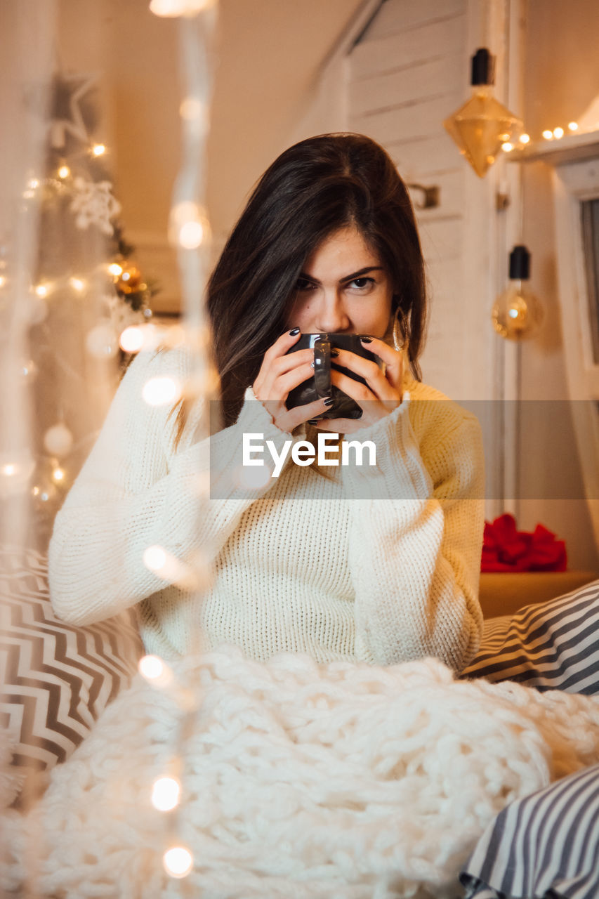 Portrait of woman drinking coffee in illuminated room