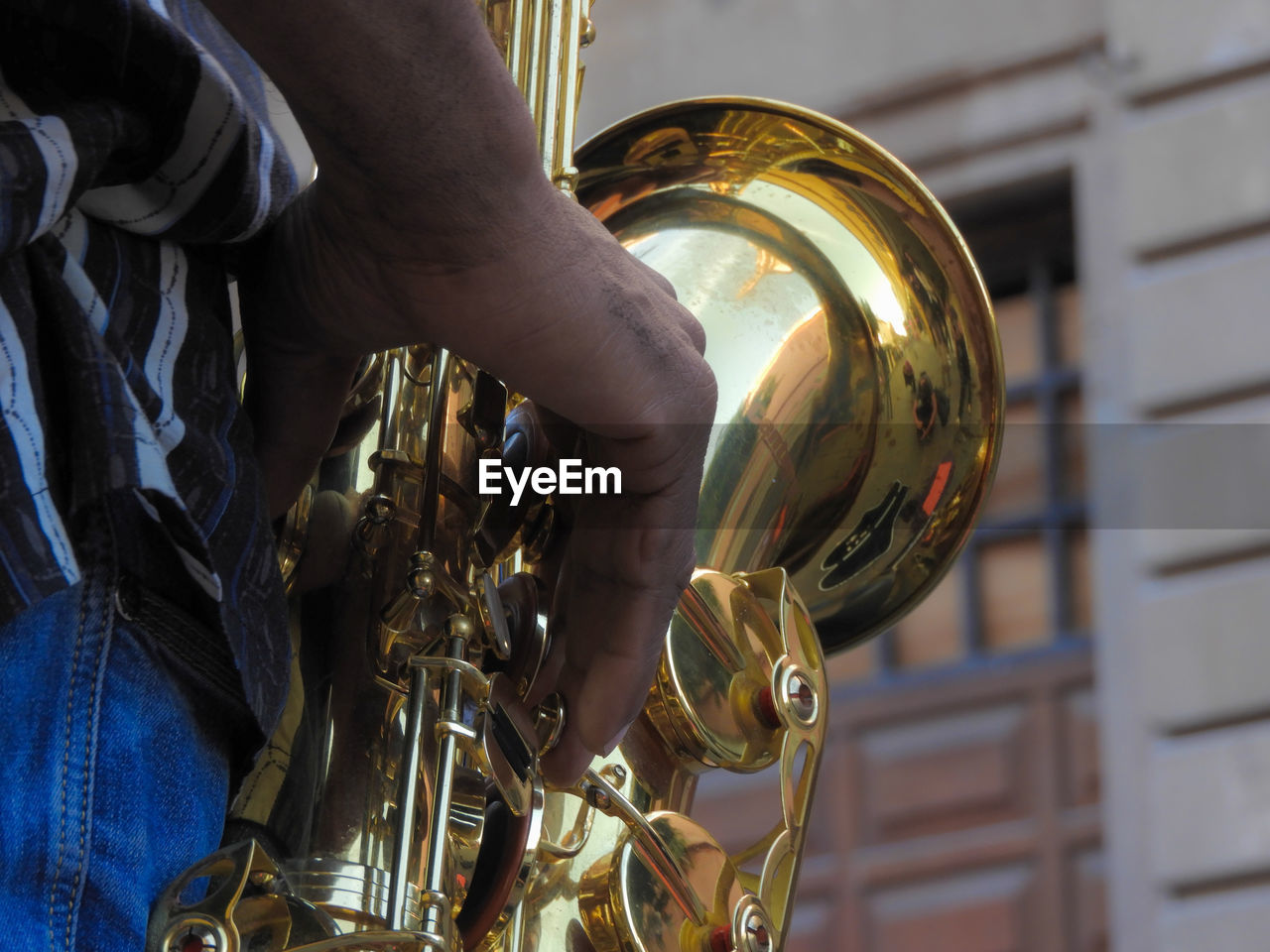 Cropped hand of musician playing saxophone outdoors