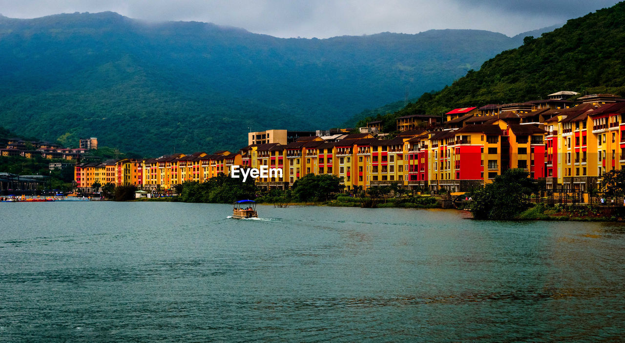 SCENIC VIEW OF SEA BY BUILDINGS AGAINST MOUNTAIN