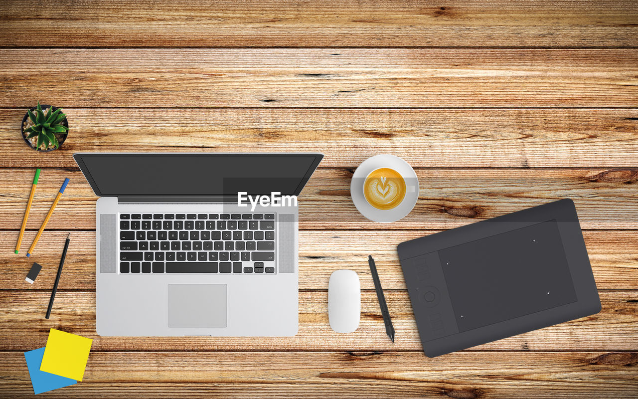 Directly above shot of coffee cup with laptop and digital tablet on table