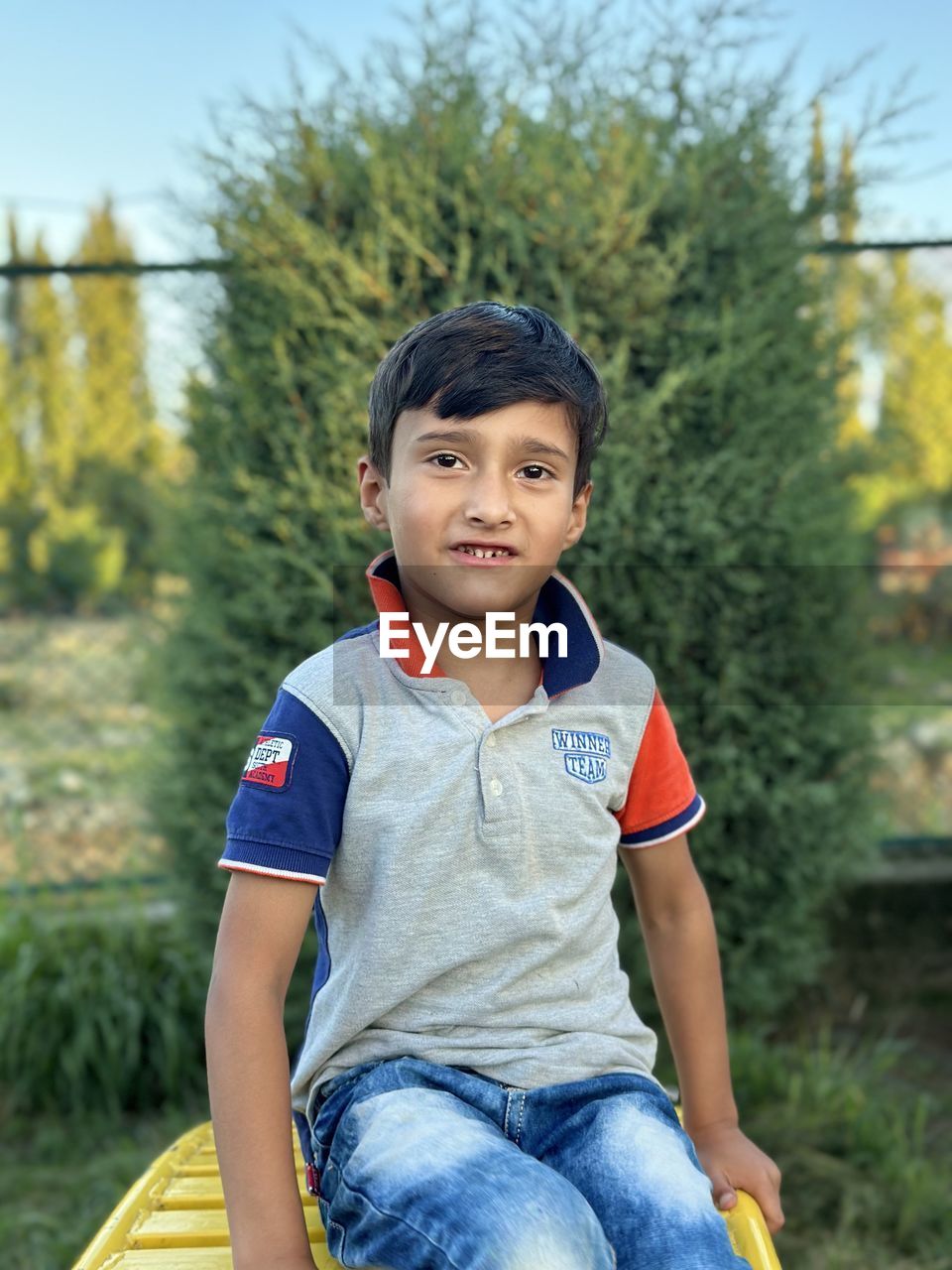 child, childhood, one person, men, casual clothing, portrait, teenager, looking at camera, person, tree, smiling, emotion, sitting, leisure activity, nature, three quarter length, plant, front view, lifestyles, happiness, day, sports, outdoors, relaxation, jeans, clothing, cheerful