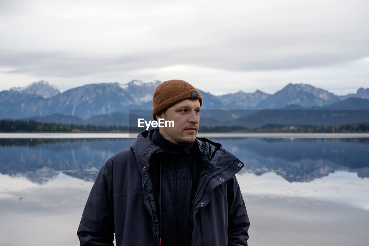 Thoughtful young man standing against lake