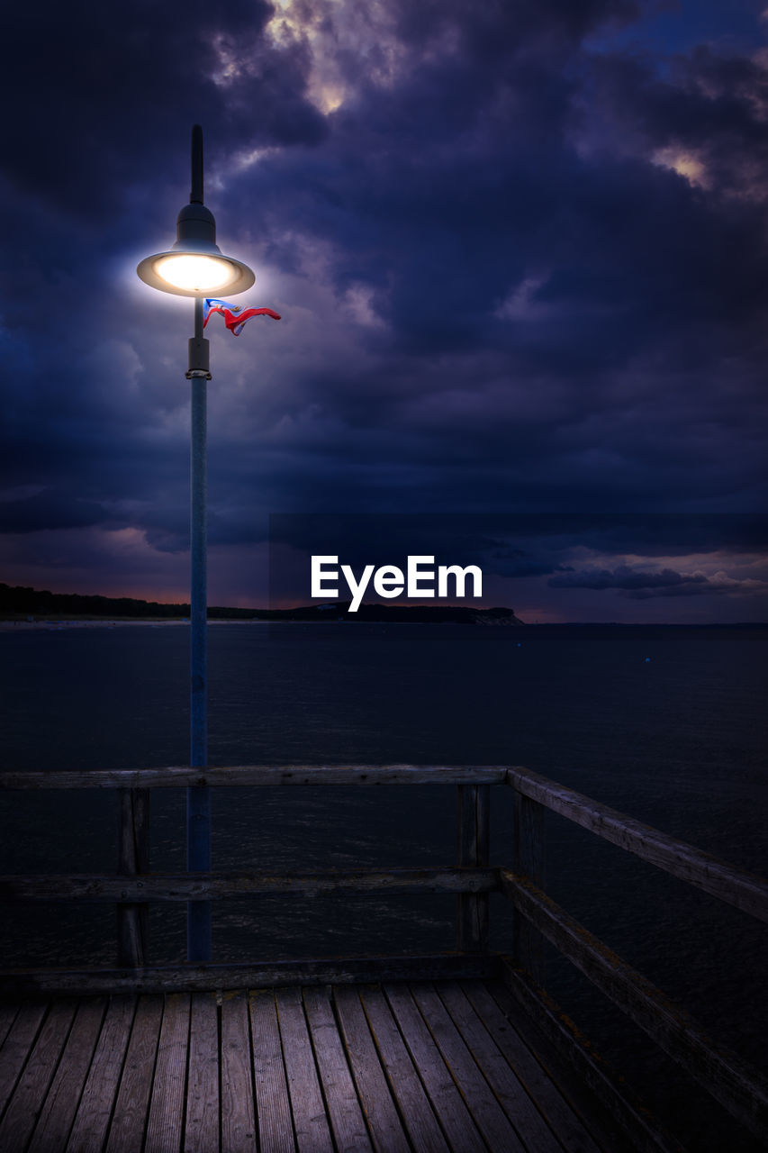 STREET LIGHTS ON PIER BY SEA AGAINST SKY