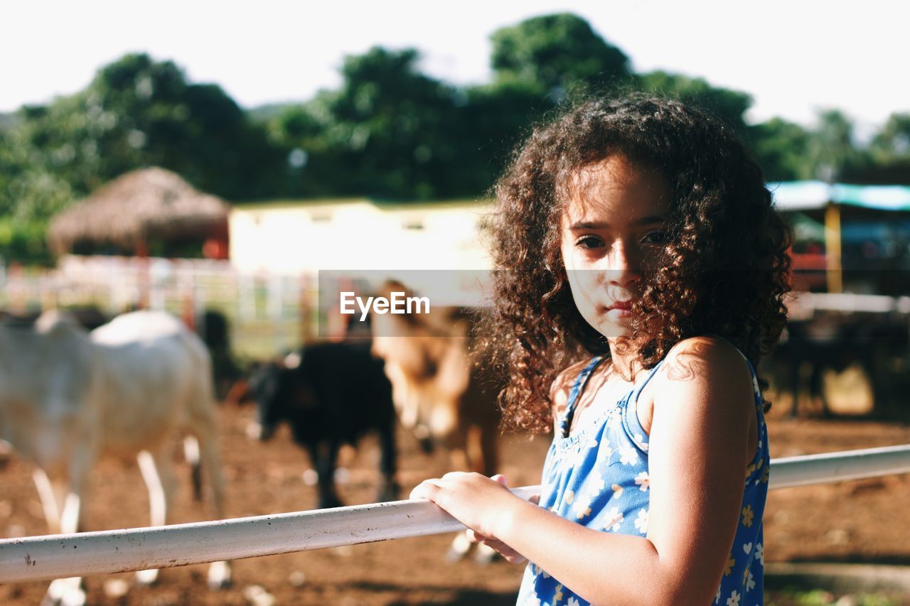 Portrait of girl standing by railing at barn