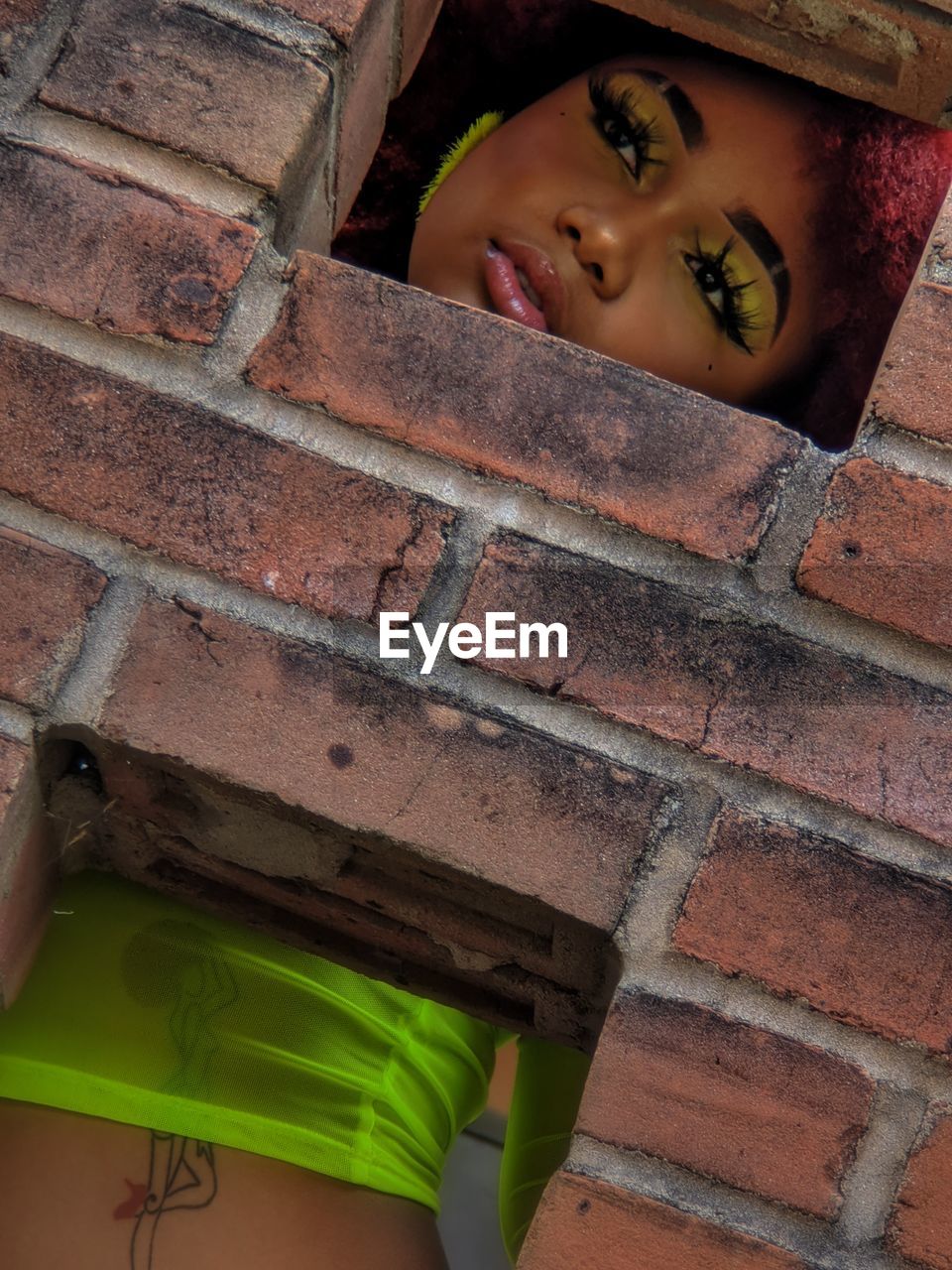 Fashionable woman seen through brick wall