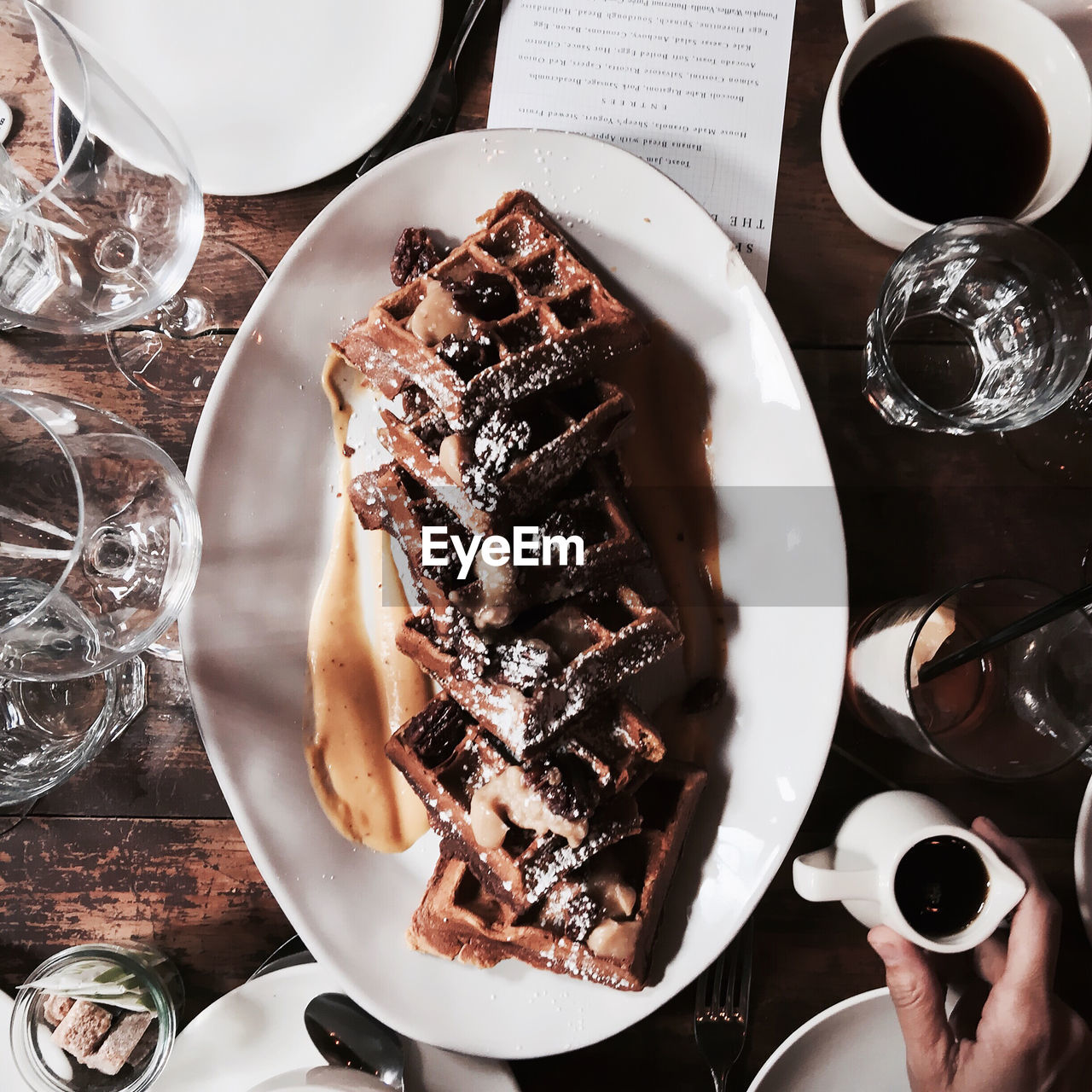 Woman holding jug with chocolate sauce for waffles