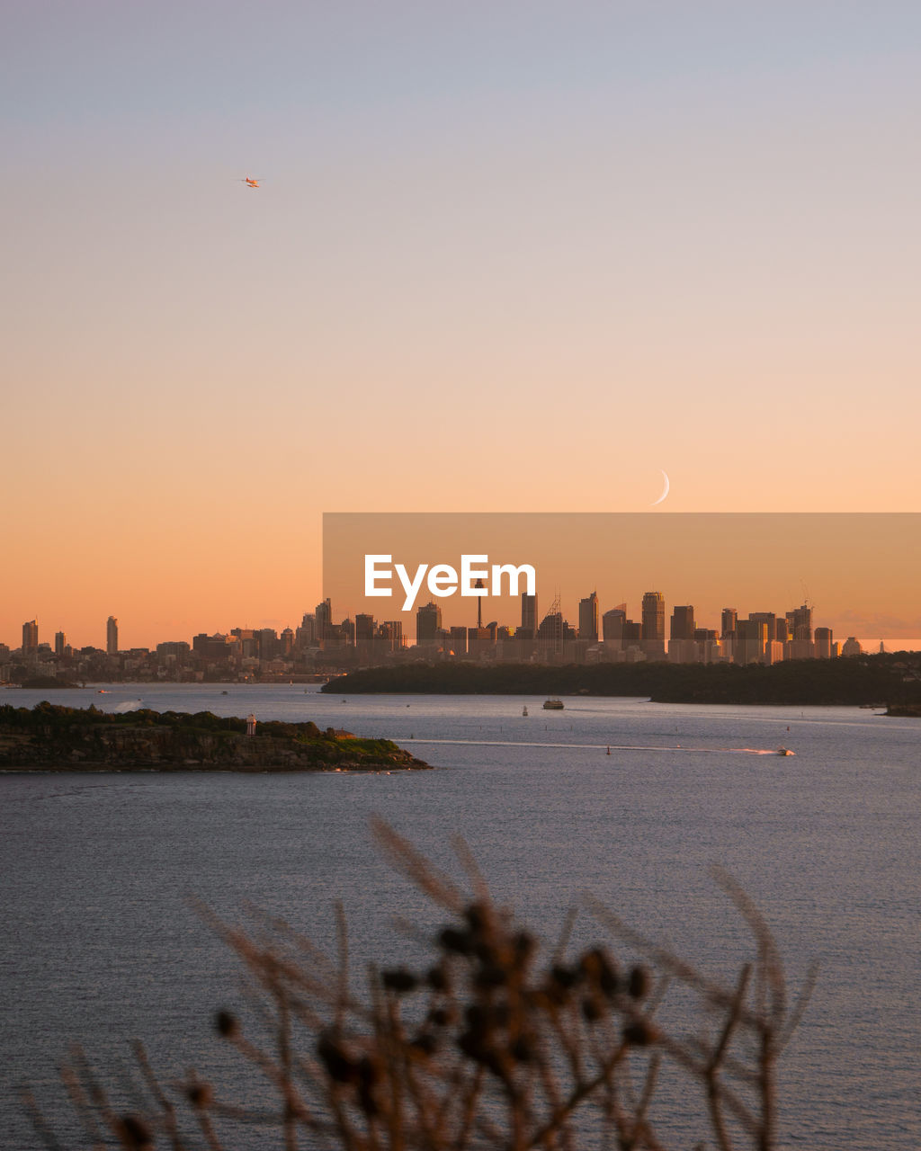 Urban skyline by river against clear sky during sunset