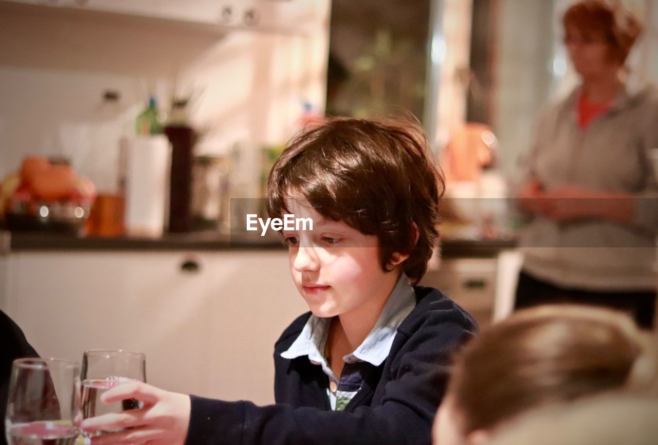 Boy holding drinking glass in kitchen