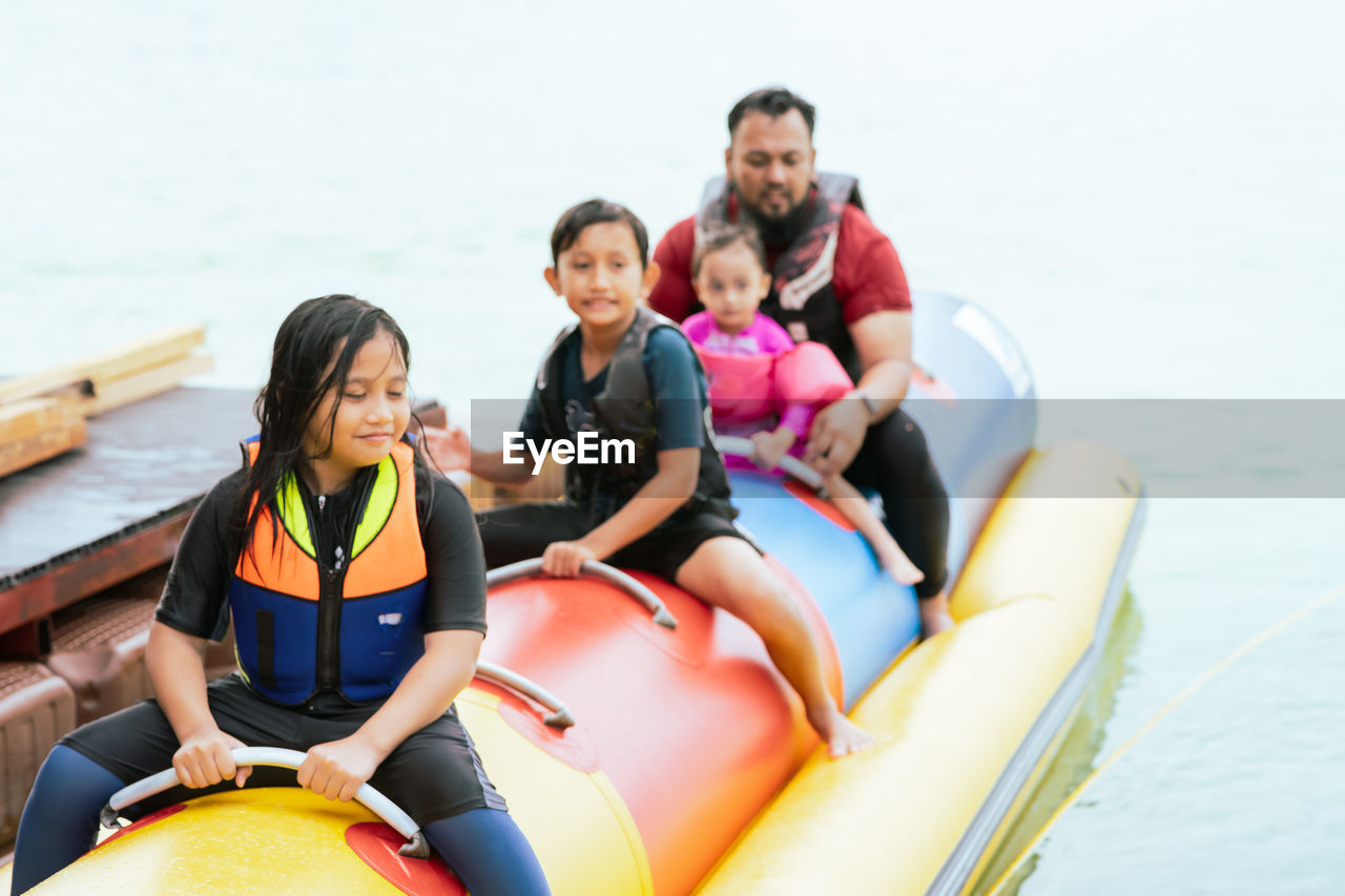 Family enjoying water activities on banana boat at the kenyir lake, terengganu, malaysia.