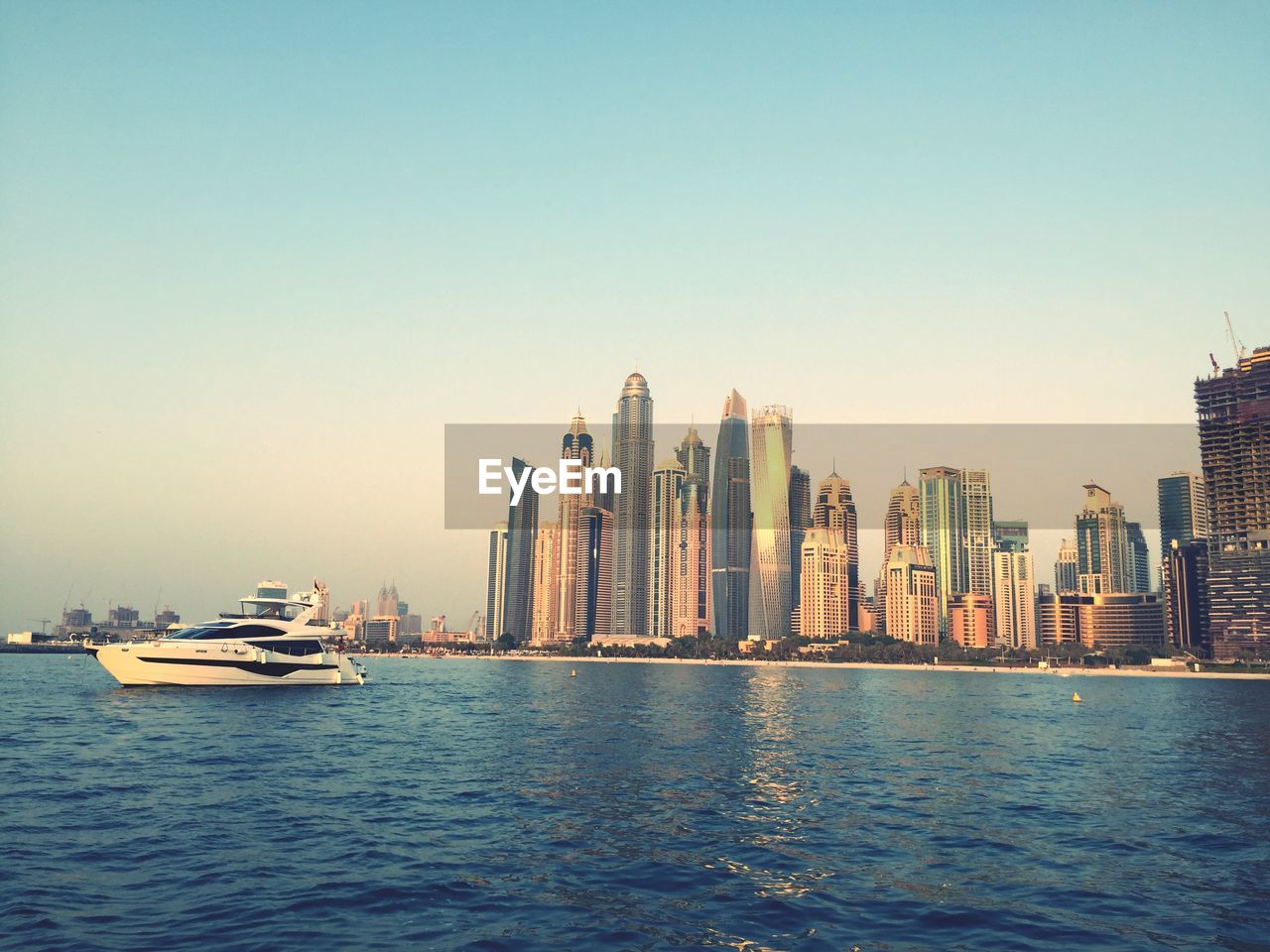 Sea and modern buildings in city against clear sky