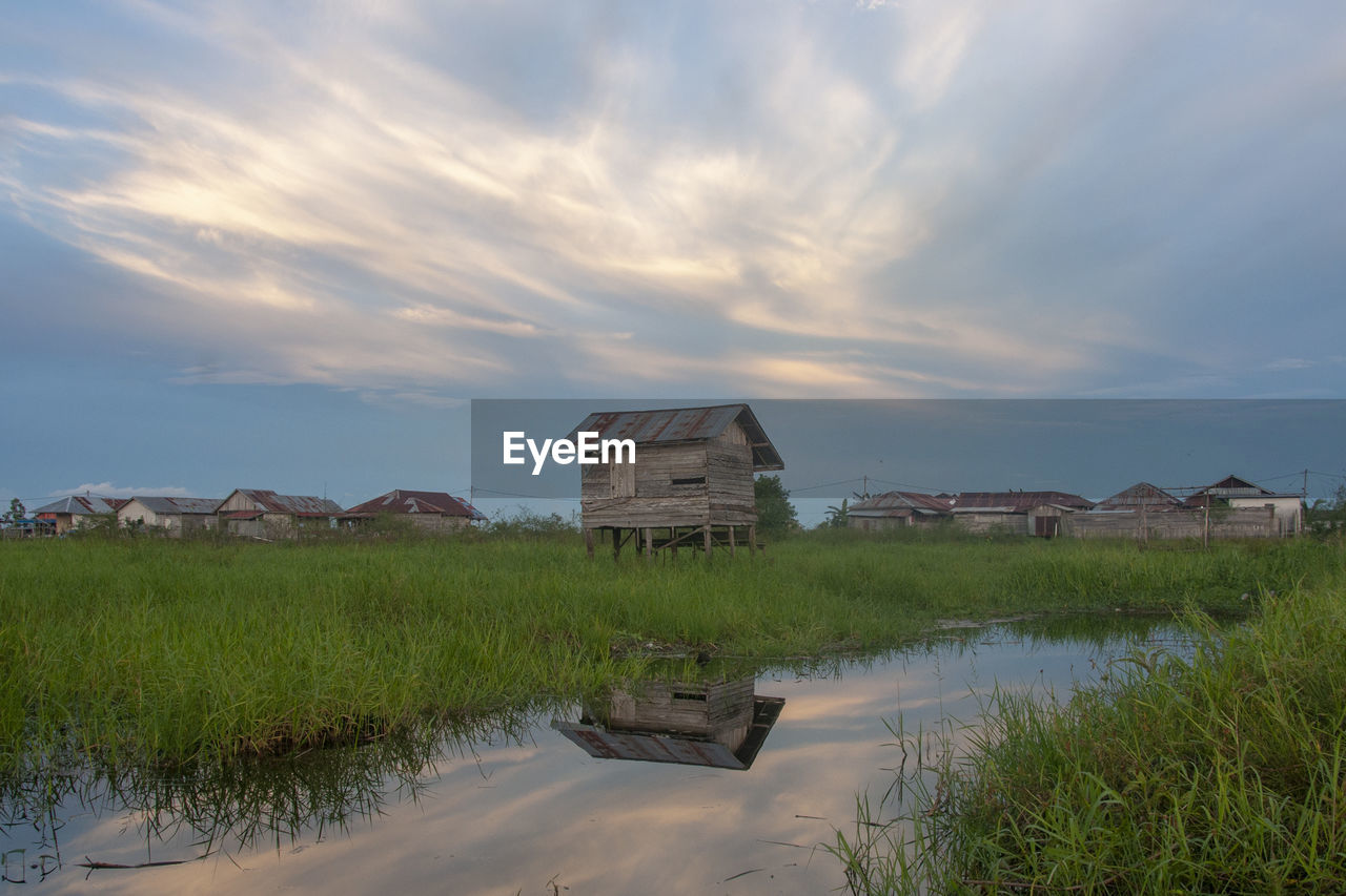 Built structure on field by buildings against sky