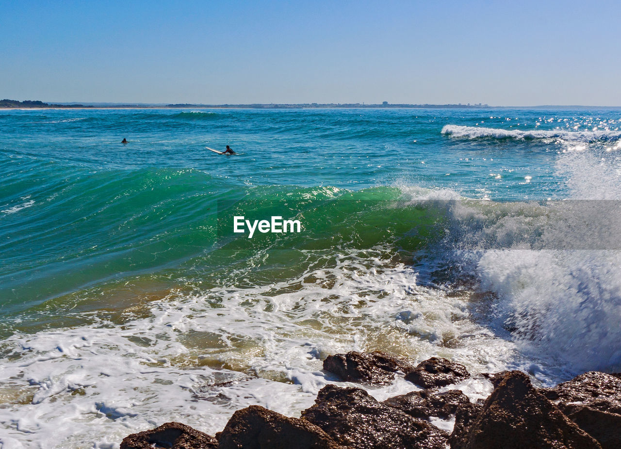 Scenic view of sea against clear sky and surfer