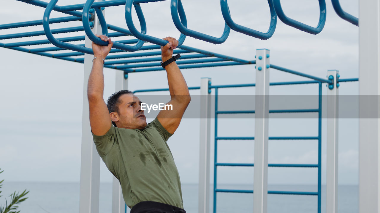 Man doing pull ups across monkey bar