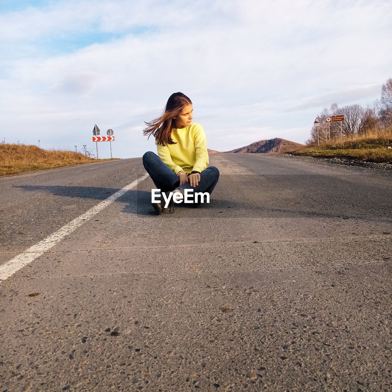 Full length of woman sitting on road